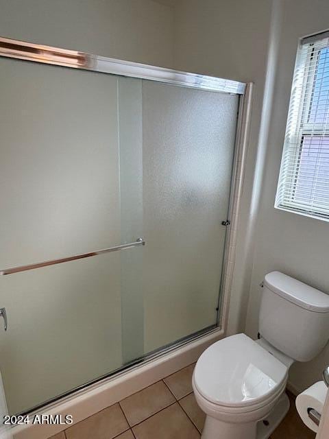 bathroom featuring toilet, tile patterned floors, and an enclosed shower