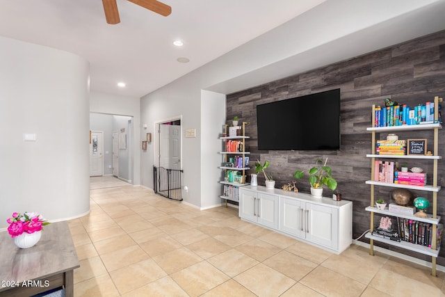 tiled living room featuring wooden walls and ceiling fan