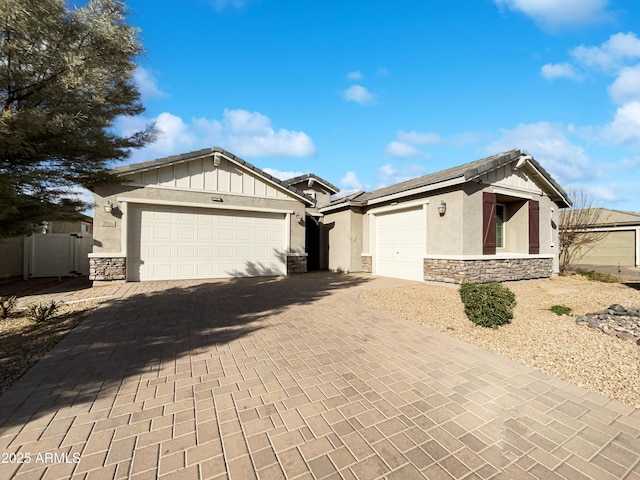 ranch-style home featuring a garage, stone siding, decorative driveway, board and batten siding, and stucco siding