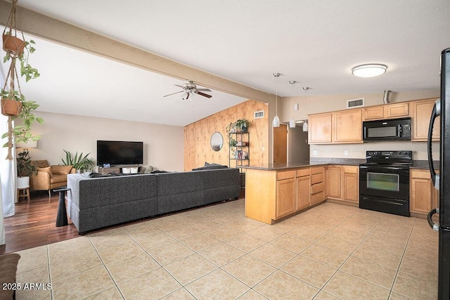 kitchen featuring black appliances, a peninsula, wood walls, a ceiling fan, and open floor plan