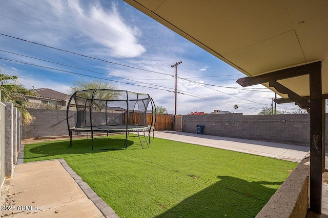 view of yard with a trampoline and a patio area
