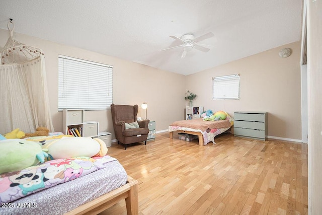 bedroom with light wood-type flooring, baseboards, lofted ceiling, and a ceiling fan