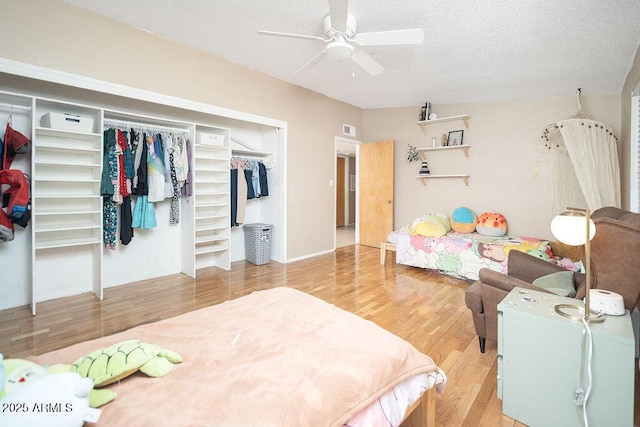 bedroom with wood finished floors, a closet, a textured ceiling, and a ceiling fan