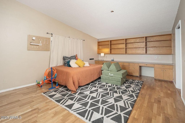 bedroom featuring light wood finished floors, baseboards, and a textured ceiling