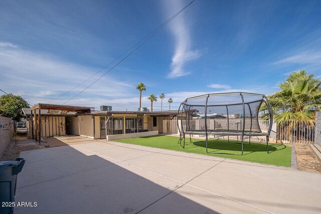 view of front of home with a trampoline and a patio