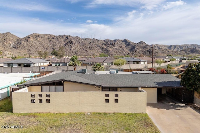 view of front of house with fence, driveway, a residential view, a carport, and a mountain view