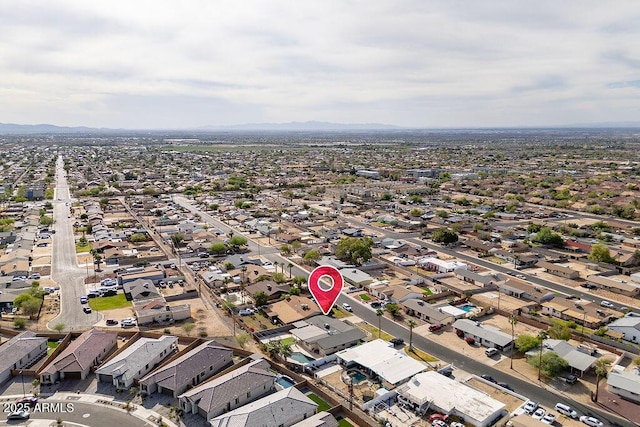 aerial view of property and surrounding area featuring nearby suburban area and a mountainous background