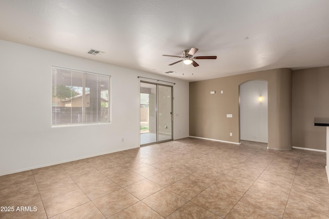 8848 W Cordes Rd, Tolleson, AZ 85353 - spare room with plenty of natural light, arched walkways, a ceiling fan, and light tile patterned flooring