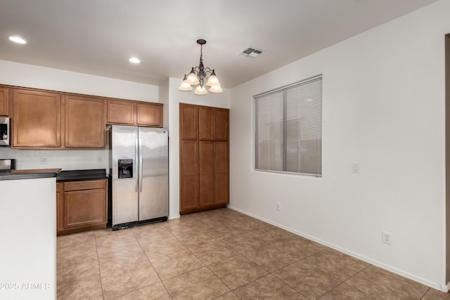 8848 W Cordes Rd, Tolleson, AZ 85353 - kitchen featuring stainless steel appliances, brown cabinets, dark countertops, a chandelier, and baseboards