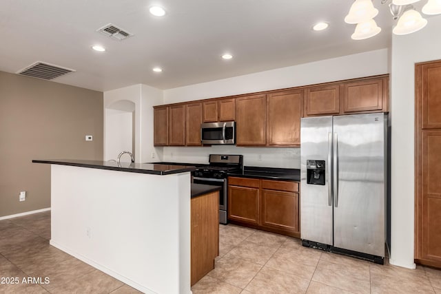 8848 W Cordes Rd, Tolleson, AZ 85353 - kitchen featuring appliances with stainless steel finishes, dark countertops, brown cabinetry, a center island with sink, and recessed lighting