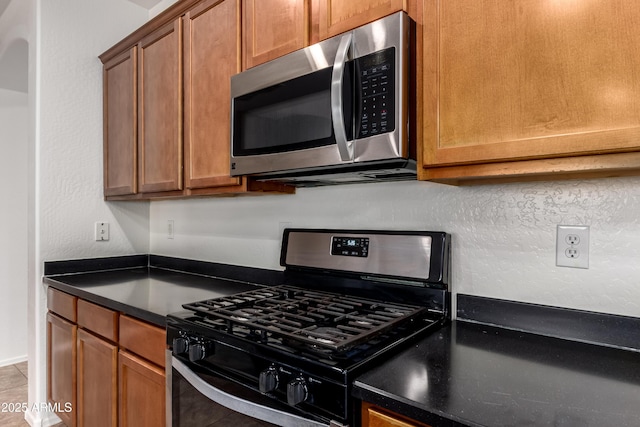 8848 W Cordes Rd, Tolleson, AZ 85353 - kitchen with appliances with stainless steel finishes, dark countertops, and brown cabinets