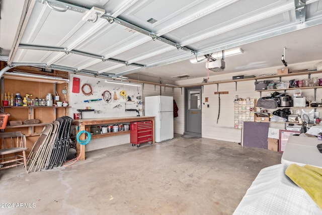 garage featuring a workshop area, white fridge, and a garage door opener