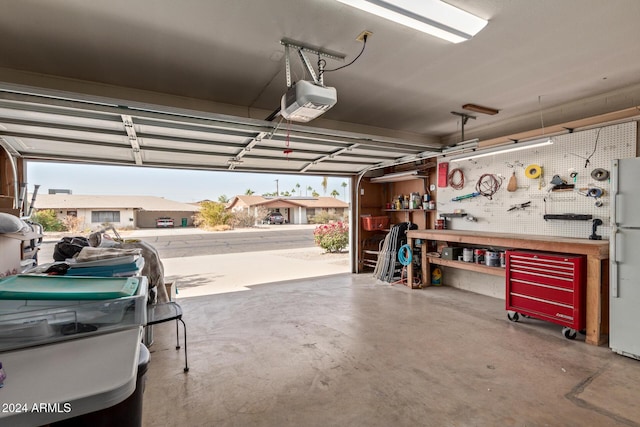 garage featuring a workshop area, white fridge, and a garage door opener