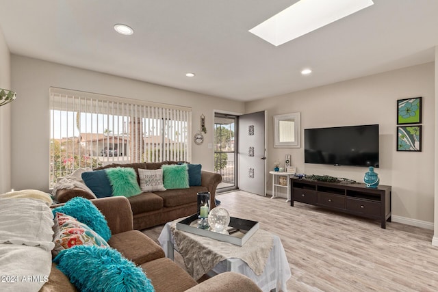 living room featuring a healthy amount of sunlight, a skylight, and light hardwood / wood-style flooring