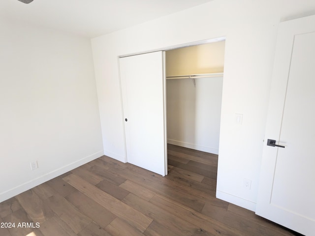 unfurnished bedroom featuring dark wood-type flooring and a closet