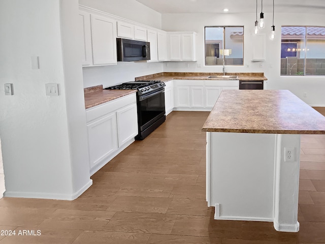 kitchen featuring white cabinets, appliances with stainless steel finishes, a center island, and sink