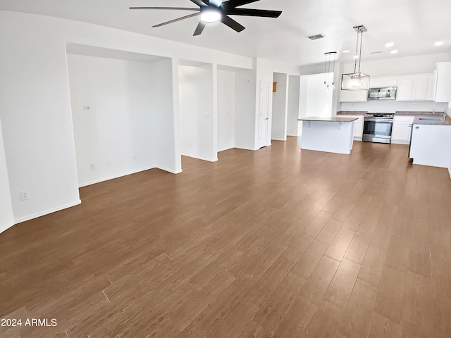 unfurnished living room featuring ceiling fan, sink, and dark wood-type flooring