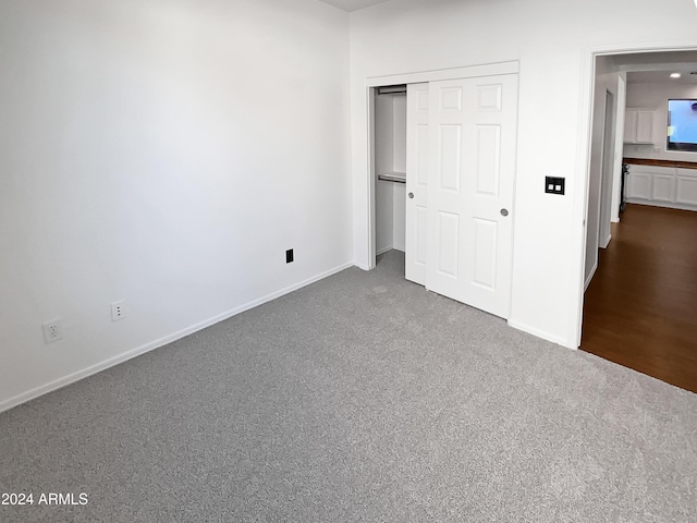 unfurnished bedroom featuring a closet and dark carpet