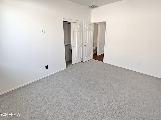 unfurnished bedroom with dark colored carpet and a closet