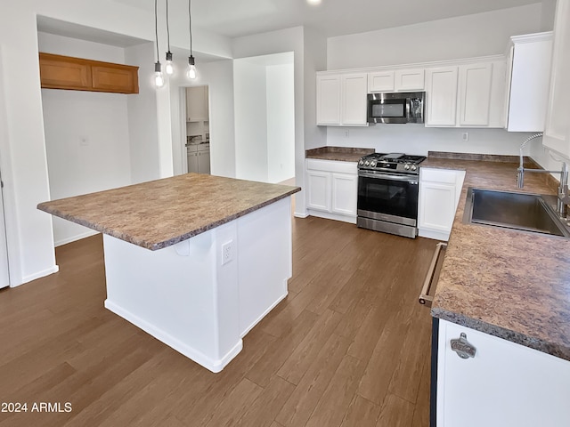 kitchen featuring appliances with stainless steel finishes, sink, white cabinets, dark hardwood / wood-style floors, and a kitchen island