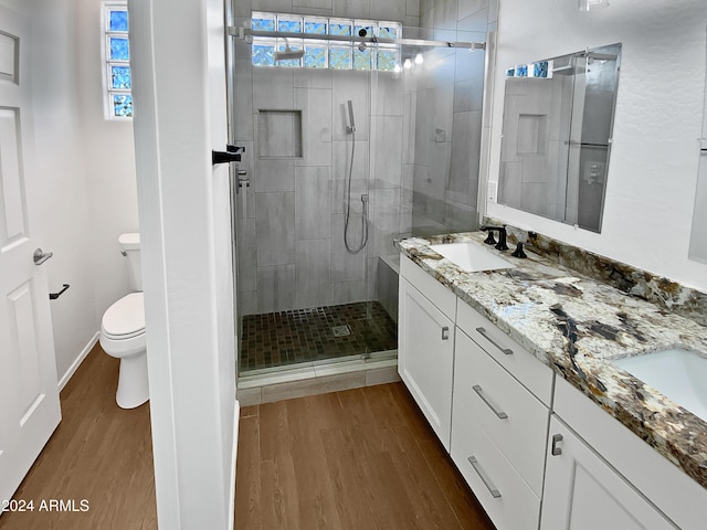 bathroom with a shower with door, vanity, wood-type flooring, and toilet