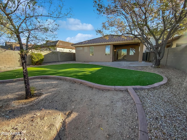 rear view of property featuring a lawn and a patio area