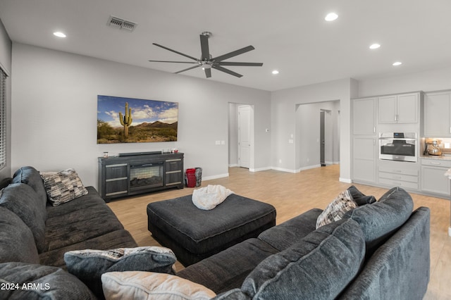 living room with a fireplace, light hardwood / wood-style floors, and ceiling fan