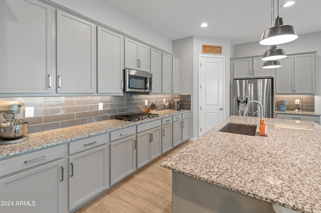 kitchen featuring light stone counters, sink, decorative light fixtures, and appliances with stainless steel finishes