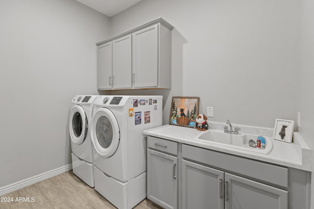 laundry room with cabinets, washer and clothes dryer, sink, and light wood-type flooring