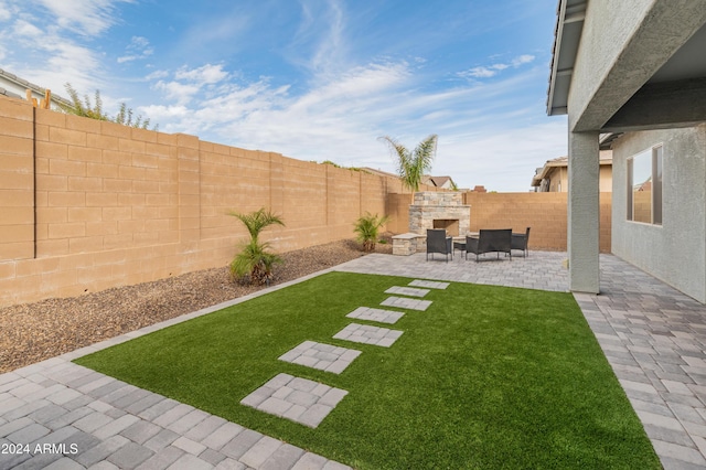 view of yard with a patio area and an outdoor stone fireplace