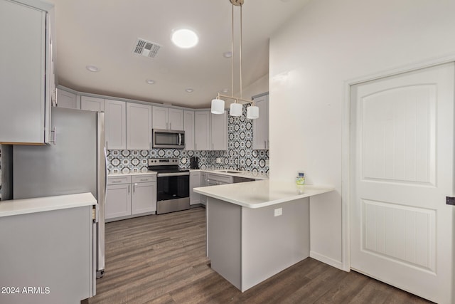 kitchen with appliances with stainless steel finishes, hanging light fixtures, dark hardwood / wood-style flooring, and tasteful backsplash