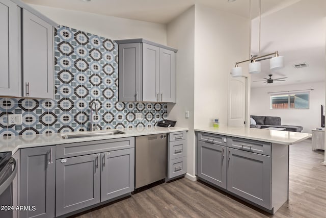 kitchen featuring sink, kitchen peninsula, stainless steel dishwasher, gray cabinets, and dark hardwood / wood-style flooring