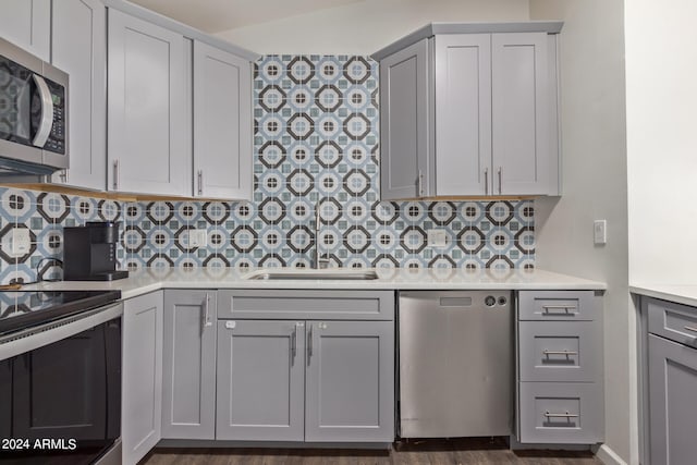 kitchen with gray cabinets, appliances with stainless steel finishes, backsplash, and dark hardwood / wood-style flooring