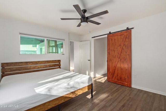 unfurnished bedroom with ceiling fan, dark hardwood / wood-style floors, and a barn door