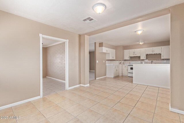 12547 W Warner St, Avondale, AZ 85323 - kitchen with white range with electric stovetop, light tile patterned floors, white cabinetry, light countertops, and brick wall