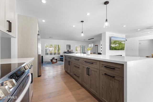 kitchen with light hardwood / wood-style floors, stainless steel appliances, ceiling fan, and hanging light fixtures