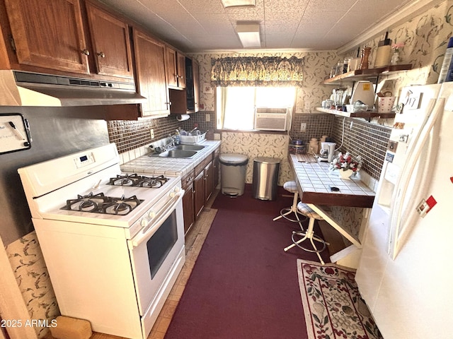 1025 N Sartillion Ave, Ajo, AZ 85321 - kitchen featuring white appliances, under cabinet range hood, tile countertops, wallpapered walls, and open shelves
