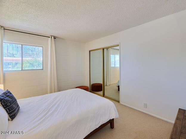 bedroom featuring a textured ceiling, light colored carpet, and a closet