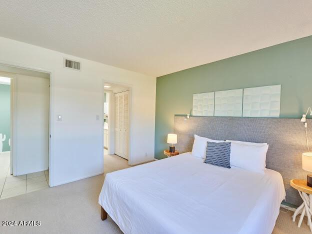 bedroom with a textured ceiling, a closet, and light tile patterned floors