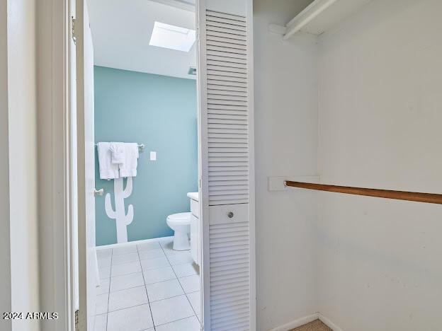 bathroom with a skylight, tile patterned floors, and toilet