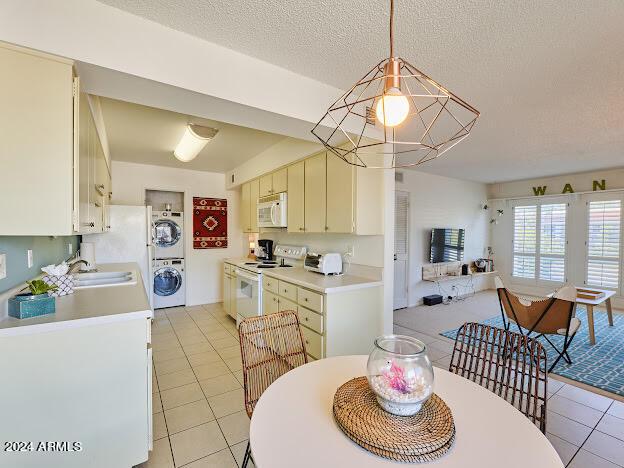 dining area with stacked washer and clothes dryer, sink, a textured ceiling, and light tile patterned floors