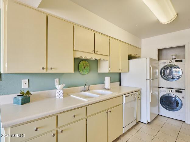 kitchen featuring sink, cream cabinets, dishwasher, and stacked washer and dryer