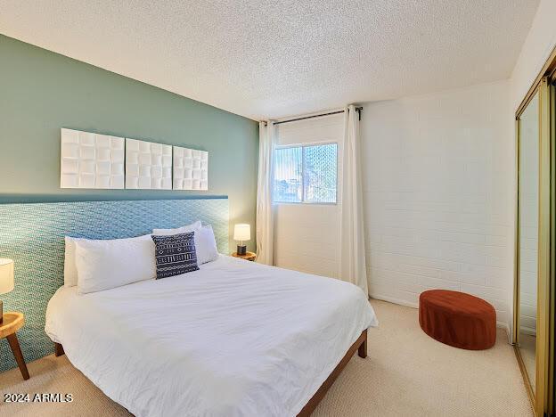 carpeted bedroom with a textured ceiling and a closet