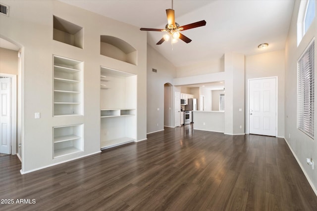 unfurnished living room featuring dark wood finished floors, built in features, a ceiling fan, and arched walkways