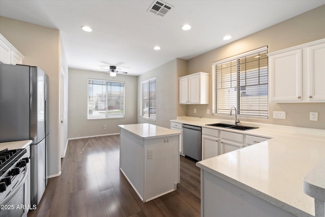 kitchen with a ceiling fan, visible vents, a kitchen island, a sink, and appliances with stainless steel finishes