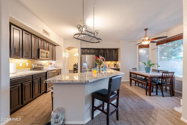 288 W Los Alamos St, Gilbert, AZ 85233 - kitchen featuring stainless steel appliances, light wood-style floors, arched walkways, and dark brown cabinetry