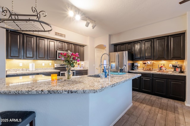 288 W Los Alamos St, Gilbert, AZ 85233 - kitchen with stainless steel appliances, arched walkways, a sink, decorative backsplash, and light stone counters