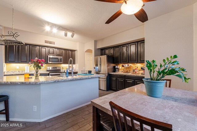 288 W Los Alamos St, Gilbert, AZ 85233 - kitchen featuring stainless steel appliances, a sink, dark wood-style floors, decorative backsplash, and arched walkways