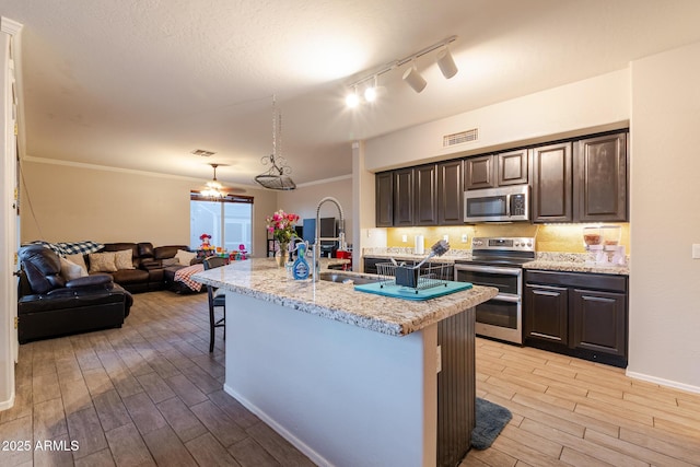 288 W Los Alamos St, Gilbert, AZ 85233 - kitchen featuring appliances with stainless steel finishes, light wood-style flooring, a kitchen bar, dark brown cabinets, and track lighting