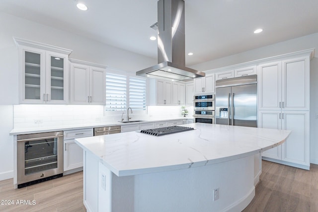 kitchen with island range hood, a kitchen island, wine cooler, stainless steel appliances, and white cabinets